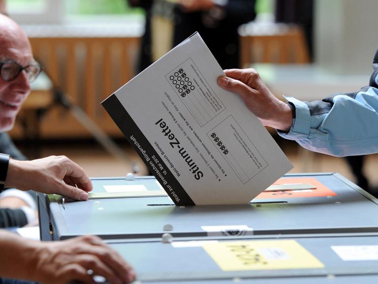 Eine Wählerin steckt ihre Stimme zur Bürgerschaftswahl in Bremen in die Wahlurne.