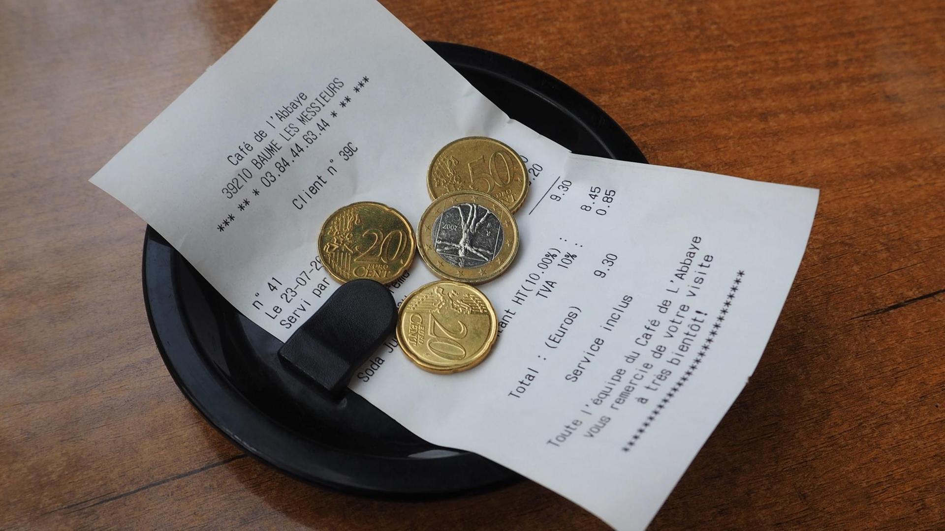 Eine Rechnung in einem Kaffee auf einem Tellerchen - darauf liegt etwas Trinkgeld Eine Rechnung in einem Kaffee auf einem Tellerchen - darauf liegt etwas Trinkgeld