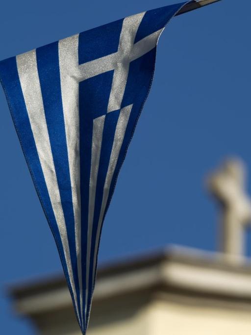 Die griechische Flagge weht vor einer Kirche.