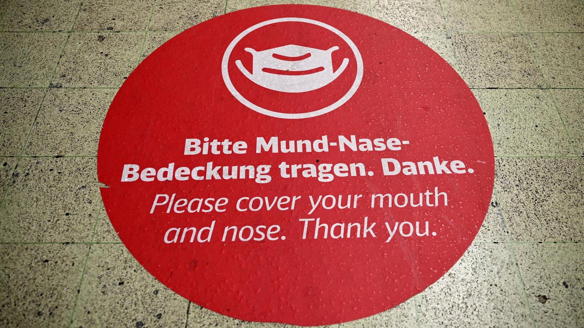 Am Boden ist das rote Bild einer Maske zu sehen und dazu der Hinweis: "Bitte Mund-Nase-Bedeckung tragen. Danke".