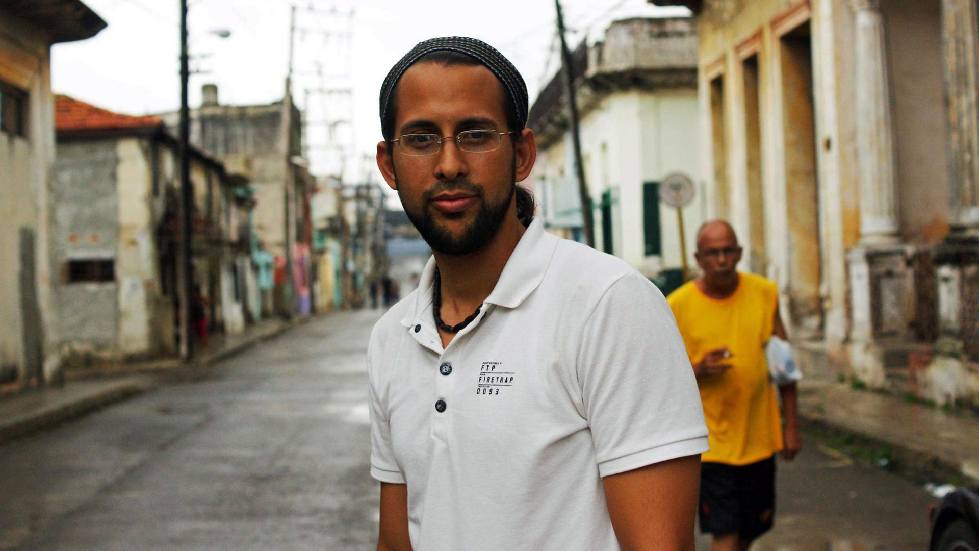 Ein junger Mann steht auf der Straße und schaut in die Kamera, Kuba