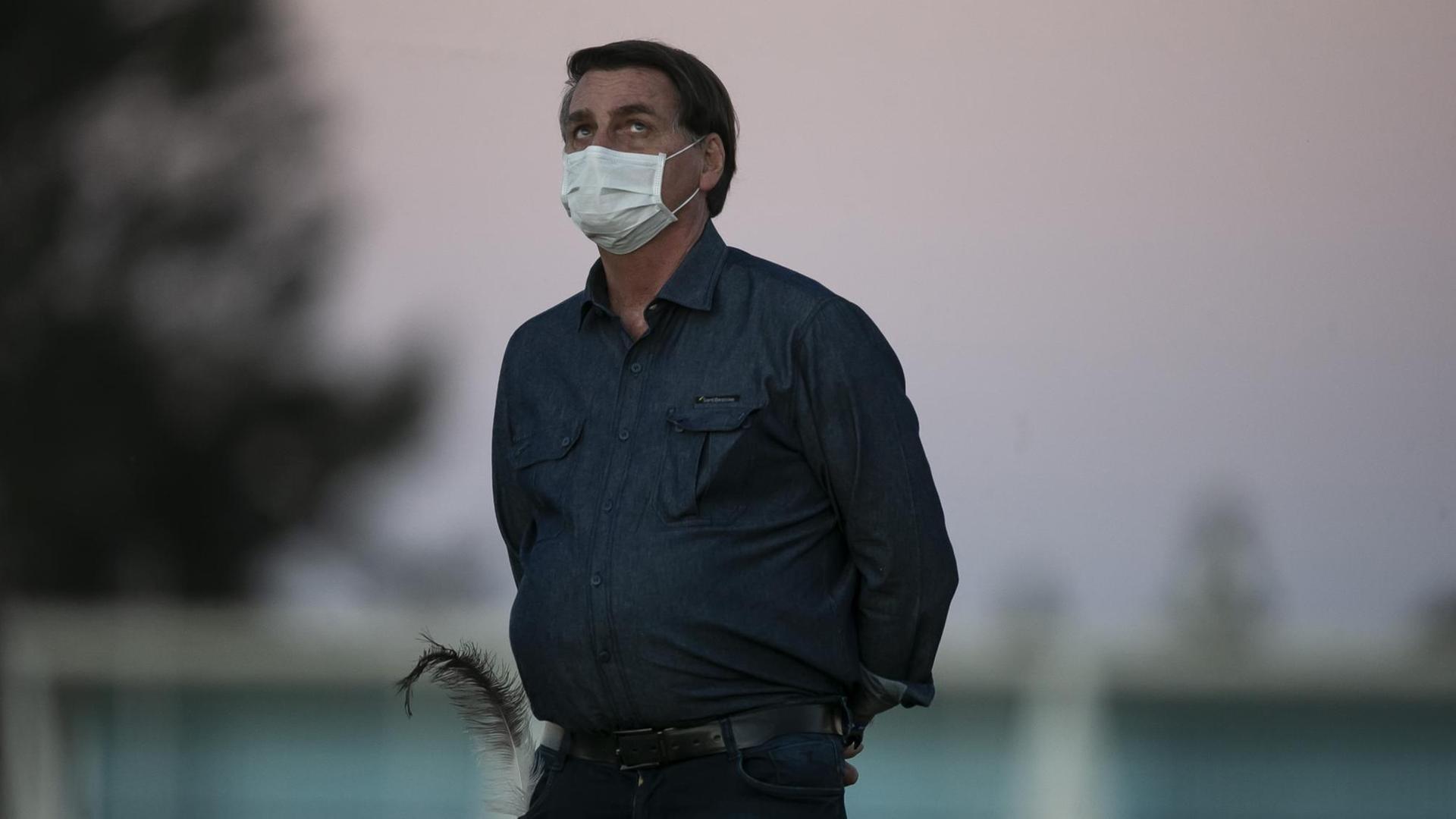 Der brasilianische Präsident schaut, mit Atemschutzmaske, während Sonnenuntergangsstimmung vor seiner offiziellen Wohnstätte, dem Avorada Palast in Brasilia, nach oben.
