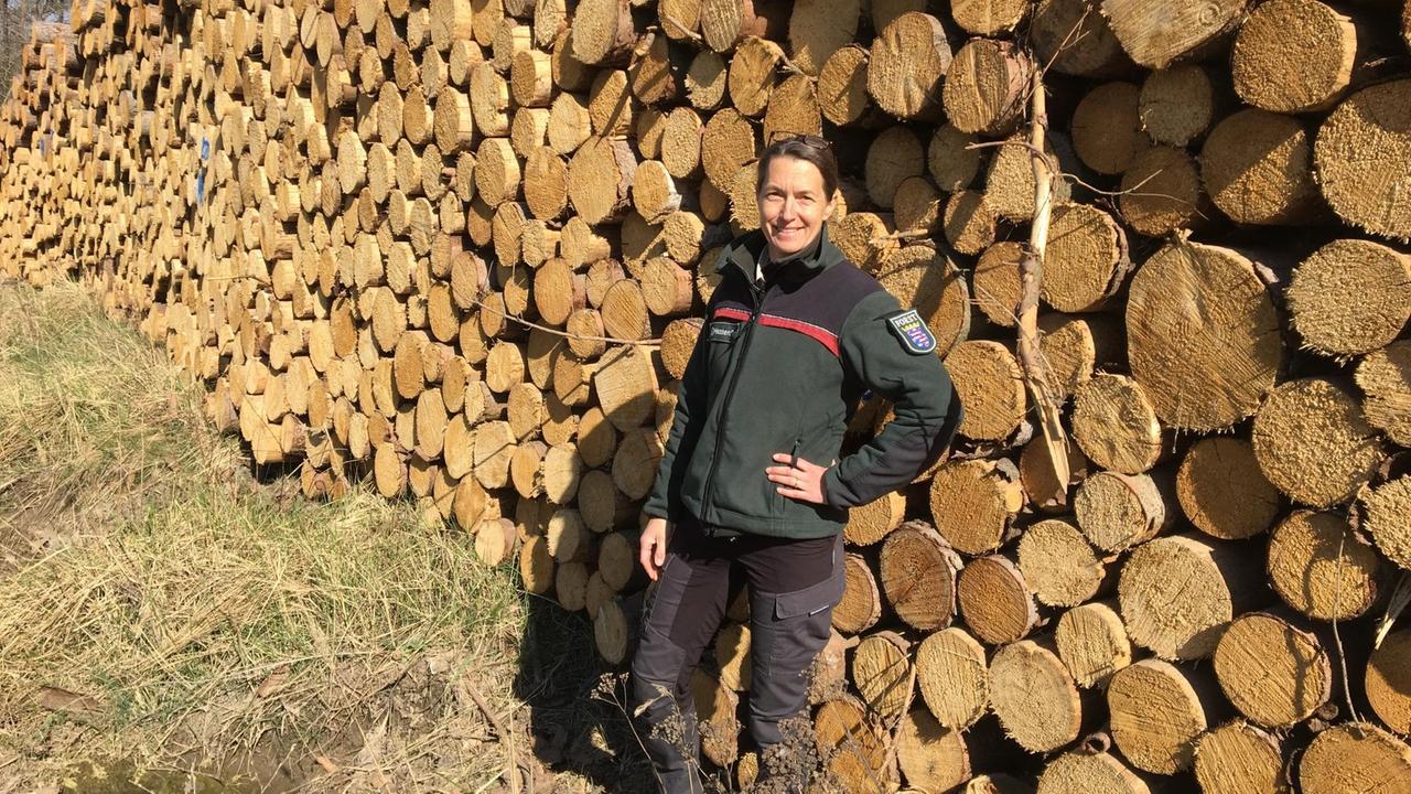 Die Forstamtsleiterin Petra Westphal steht vor einem Holzstapel.