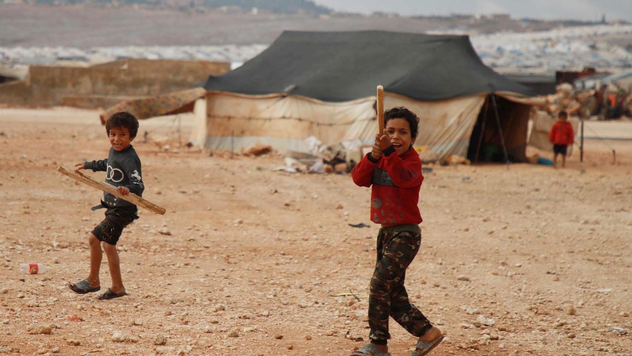 Vertriebene syrische Kinder spielen in einem Lager in der Nähe des Dorfes Kafr Lusin, in Idlibs nördlicher Landschaft nahe der syrisch-türkischen Grenze, im Freien
