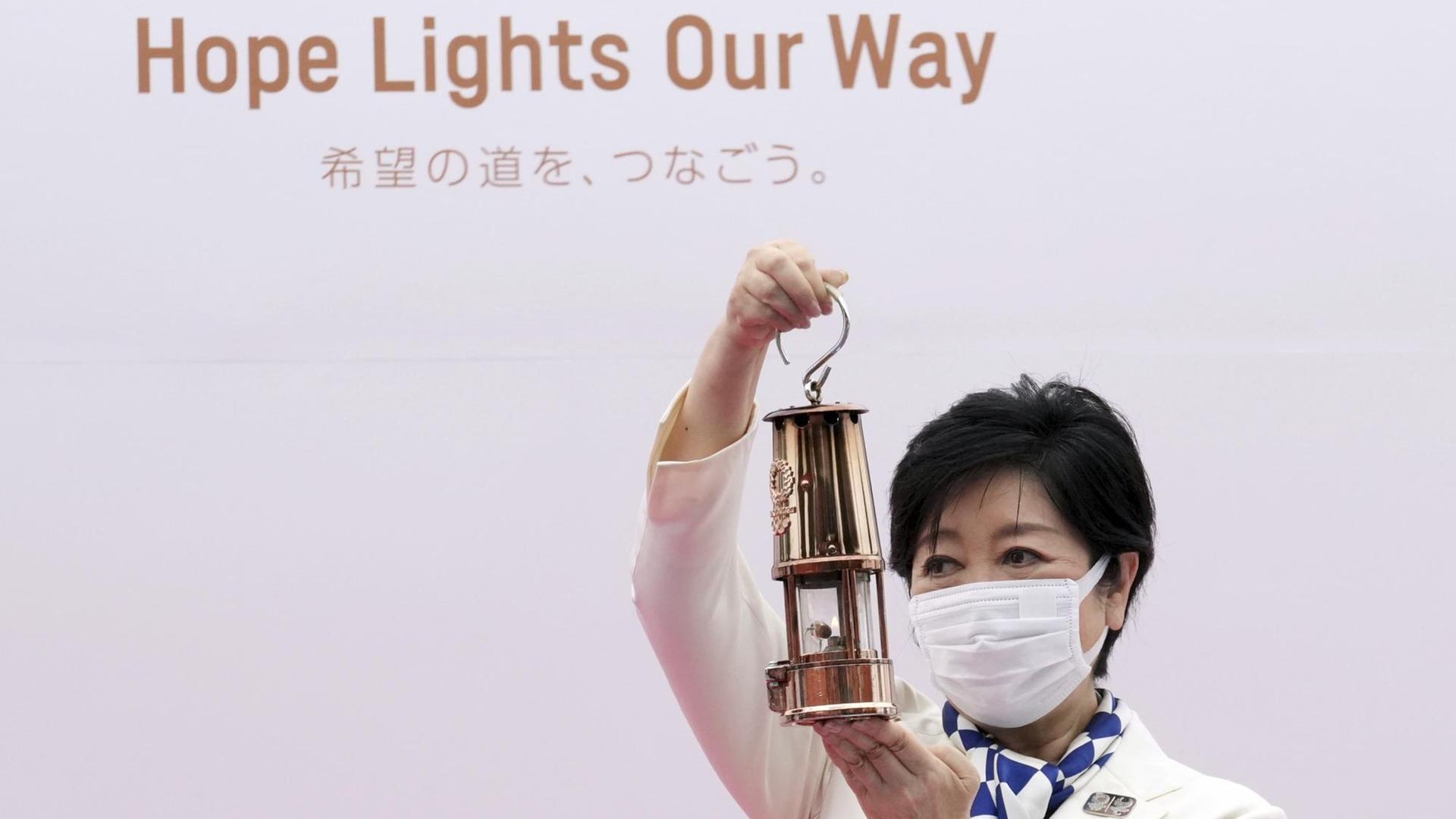 Tokios Gouverneurin Yuriko Koike hält eine Laterne mit der olympischen Flamme in die Höhe. Die Zeremonie des olympischen Fackellaufs Tokio 2020 fand im Komazawa Olympic Park statt.