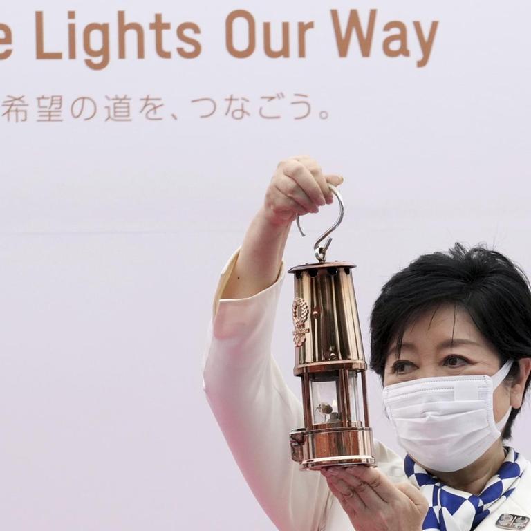 Tokios Gouverneurin Yuriko Koike hält eine Laterne mit der olympischen Flamme in die Höhe.  Die Zeremonie des olympischen Fackellaufs Tokio 2020 fand im Komazawa Olympic Park statt. 
