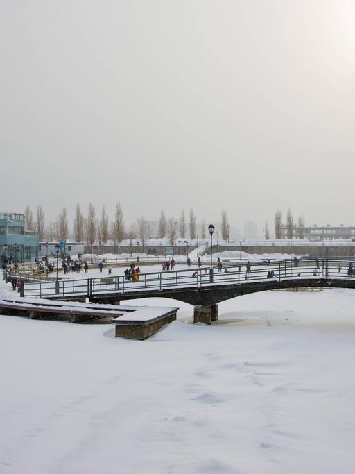 Eine schneebedeckte Brücke über einen zugefrorenen Fluss im Winter in Montreal.