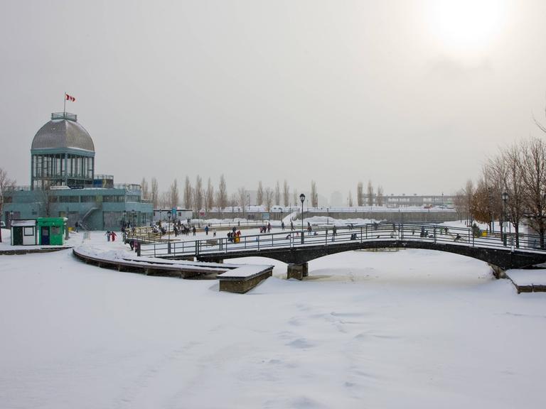 Eine schneebedeckte Brücke über einen zugefrorenen Fluss im Winter in Montreal.