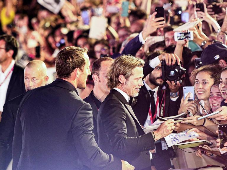 Brad Pitt gibt Fans Autogramme und ist von Fotografen umringt.