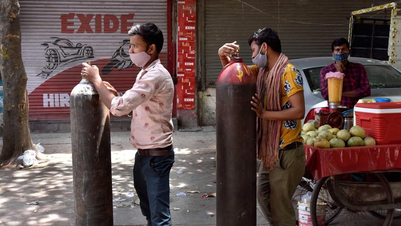 Zwei Männer gestützt auf Sauerstofflaschen warten in einer Schlange vor einem Geschäft eines Sauerstofflieferanten am 4. Mai 2021 in Neu-Delhi.