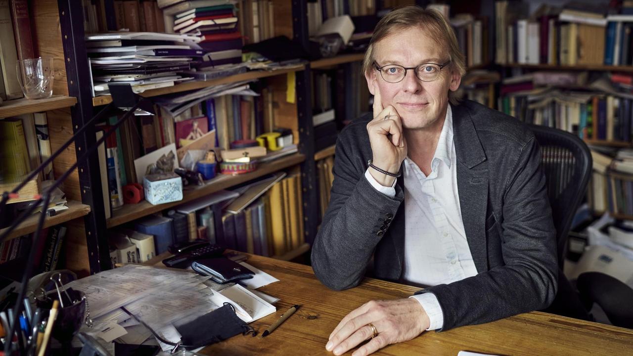 Porträt des Autoren Dieter Thomä an seinem Schreibtisch vor einem Bücherregal.