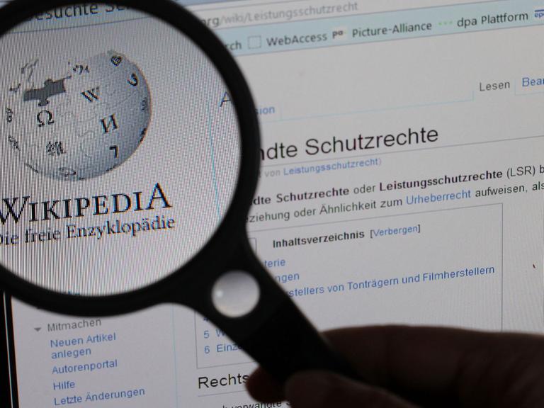 Unter einer Lupe ist am 21.06.2012 das Logo Wikipedia auf einem Computerbildschirm zu sehen.