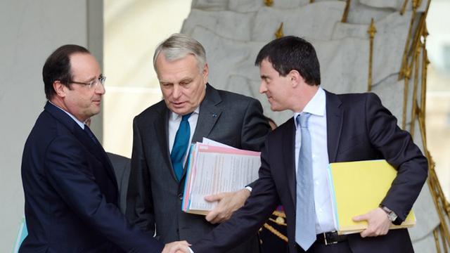 Francois Hollande (l.) reicht am 12. Juni 2013 dem damaligen Innenminister Manuel Valls (r.) die Hand. Dazwischen steht der am 31.03.2014 zurückgetretene Premierminister Jean-Marc Ayrault.