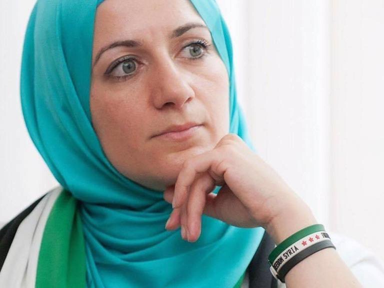 Nahla Osman mit Kopftuch, vor einem Fenster sitzend.