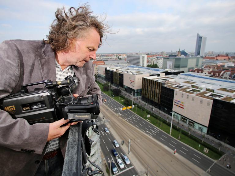 Der Journalist Siegbert Schefke steht mit seiner alten Videokamera auf dem Turm der Reformierten Kirche in Leipzig. Schefke filmte am 9. Oktober 1989 mit seinem Kollegen Aram Radomski eine Montagsdemo vom Turm der Kirche aus.