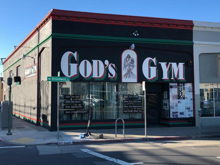 Außenansicht des "God's Gym" mit dem großen Titelschriftzug an der Wand.