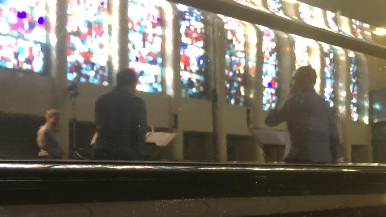 Spiegelung der Probe des Ensembles im zugeklappten Flügel in der Jesus Christus Kirche Berlin.