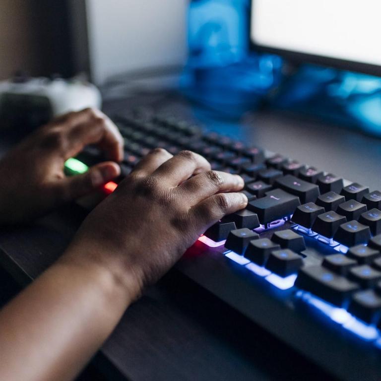 Kinderhände auf einer leuchtenden Spiele-Tastatur
