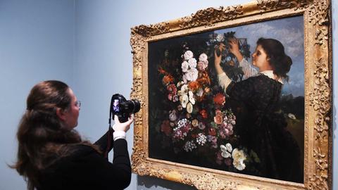 Eine Besucherin fotografiert das Gemälde "Les Trellis" von Gustave Courbet, das nach dem Vorbild des Malers Delacroix entstand. Es hängt in der Ausstellung "Delacroix and the rise of Modern art" in der National gallery in London.