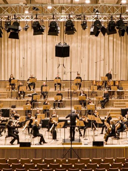 Ein nicht all zu groß besetztes Orchester spielt auf der Bühne mit Dirigenten.