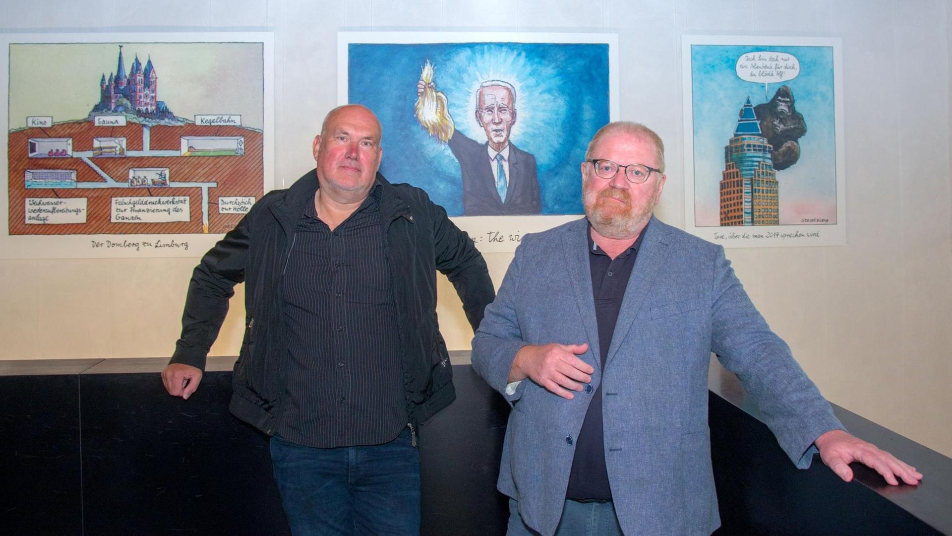 Die Zeichner Achim Greser und Heribert Lenz stehen in der Ausstellung "Ein Vierteljahrhundert Witze für Deutschland"