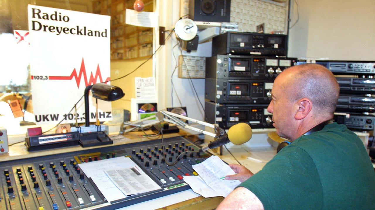 Ein Moderator des Rundfunksenders Radio Dreyeckland sitzt im Studio in Freiburg vor dem Mischpult.