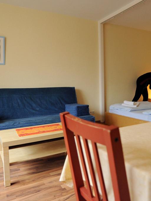 Eine Frau richtet ein Bett in einer Ferienwohnung her.
