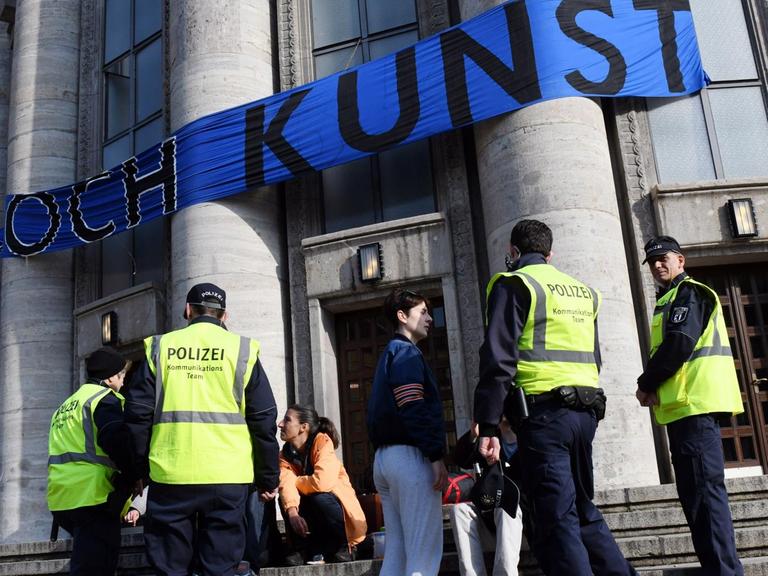 Polizisten sprechen am 28.09.2017 an der besetzten Volksbühne in Berlin mit Kunst- und Politaktivsten. Ein Transparent mit dem Schriftzug "doch Kunst" ist am Gebäude angebracht.