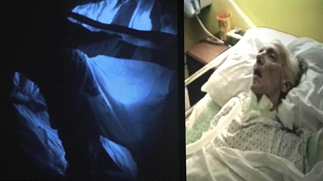 Das Bild zeigt eine Videoaufnahme einer alten, sterbenden Frau im Krankenhausbett