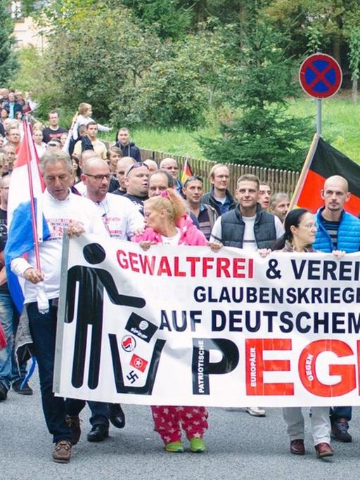 Demonstranten mit einem Pegida-Banner laufen durch Sebnitz.