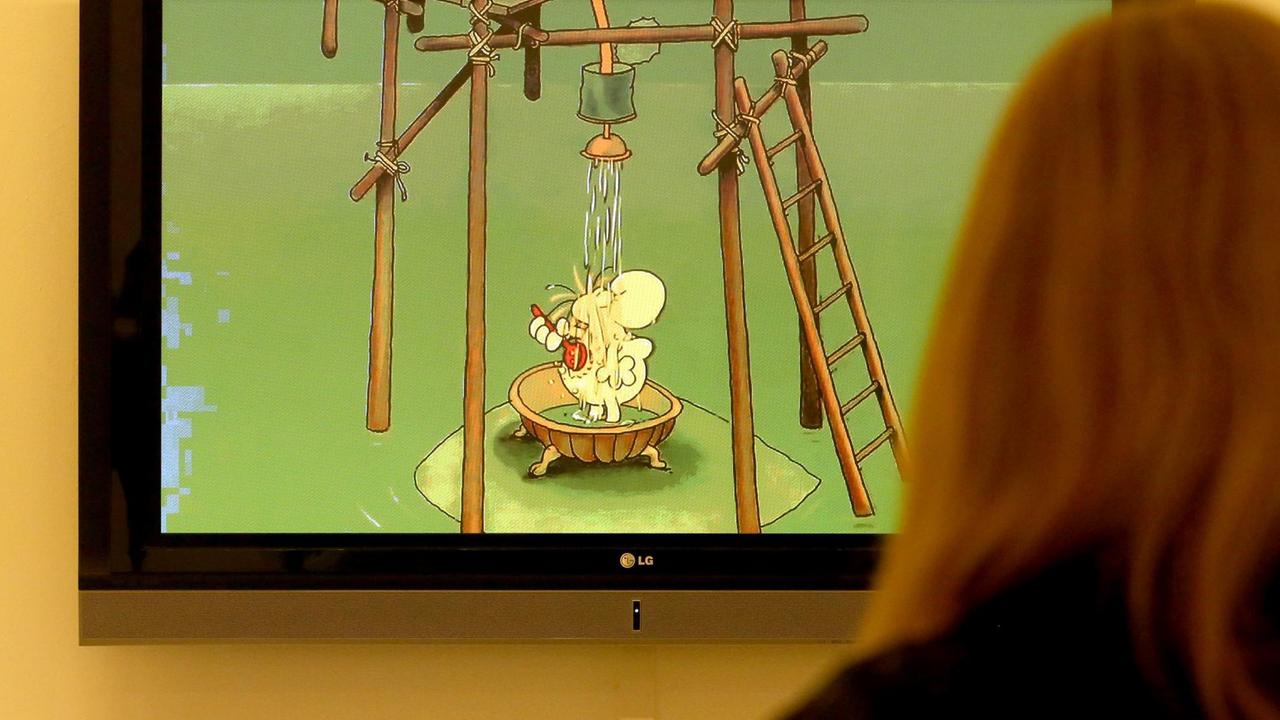 Das Bild zeigt einen Ausschnitt eines Zeichentrickfilms von Guillermo Mordillo. Die Szene zeigt eine von Mordillos Figuren mit Knollennase unter einer aus Holz zusammengebauten Dusche. 