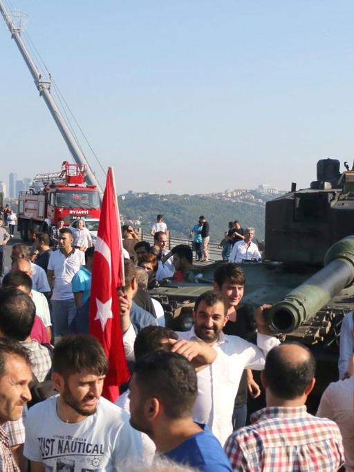 Polizisten und Erdogan-Anhänger scharen sich um einen Panzer vor der Bosporusbrücke in Istanbul.