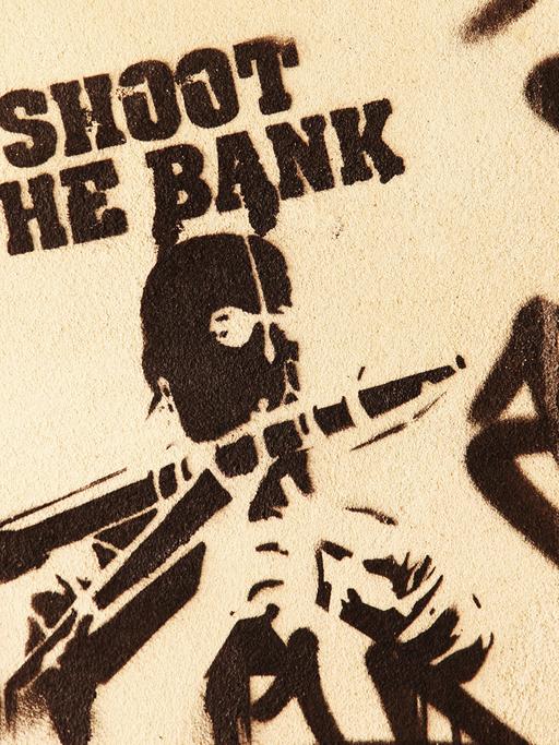 Ein gesprühtes "Stencil" zeigt die Worte "Shoot the Bank" und einen Mann mit Maske und einer Panzerfaust, aufgenommen 2012 in Berlin im Bezirk Mitte