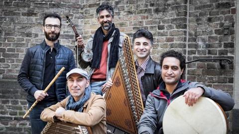 Die fünf Musiker sitzen und stehen mit ihren orientalischen Instrumenten vor einer Mauer