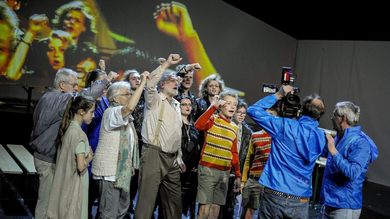 Menschen recken die Faust, gefilmt von einem Kamerateam: Szene aus dem Theaterstück "Früher war alles" des Bürgertheaters am Staatsschauspiel in Dresden.