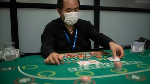 Ein angehender Croupier und Student der Japan Casino School in Tokio spielt mit Mundschutz das Karten-Glücksspiel Baccarat