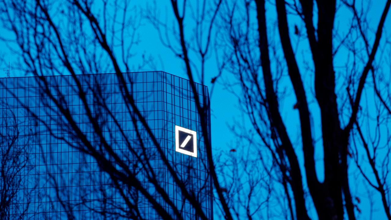 Das eine der beiden Hochhäuser der Deutschen Bank mit dem Logo des Unternmehmens, aufgenommen in der Abenddämmerung in Frankfurt am Main durch die dunklen Äste eines Baumes in der Taunusanlage, am 22.12.2012.  Foto: Wolfram Steinberg dpa