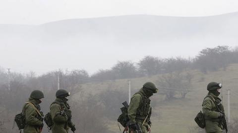 Vier bewaffnete Männer in Militäruniform gehen auf einem Weg in der Nähe der Stadt Simferopol auf der ukrainischen Halbinsel Krim.