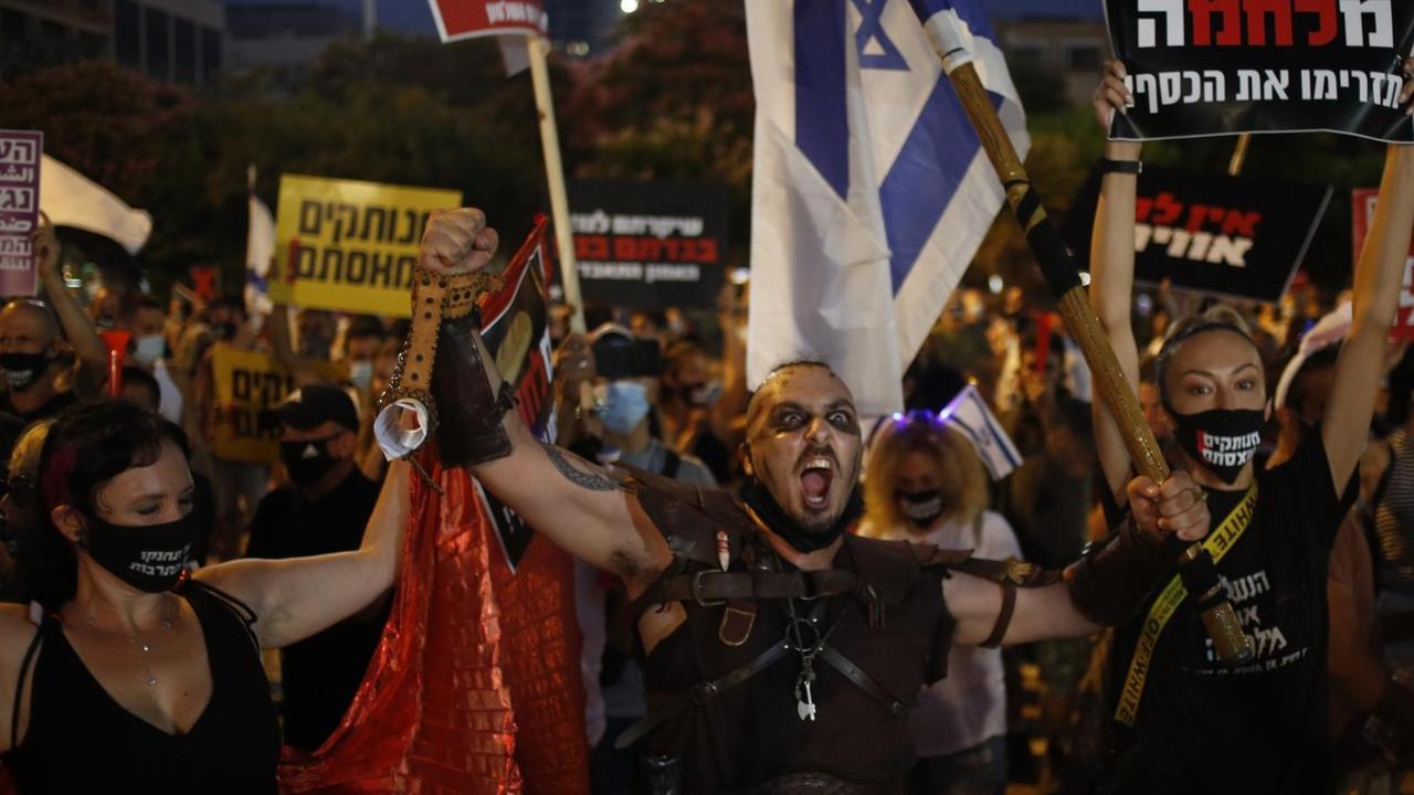 Demonstrierende mit israelischen Flaggen, zum Teil mit Mundschutz, äußern ihren Unmut