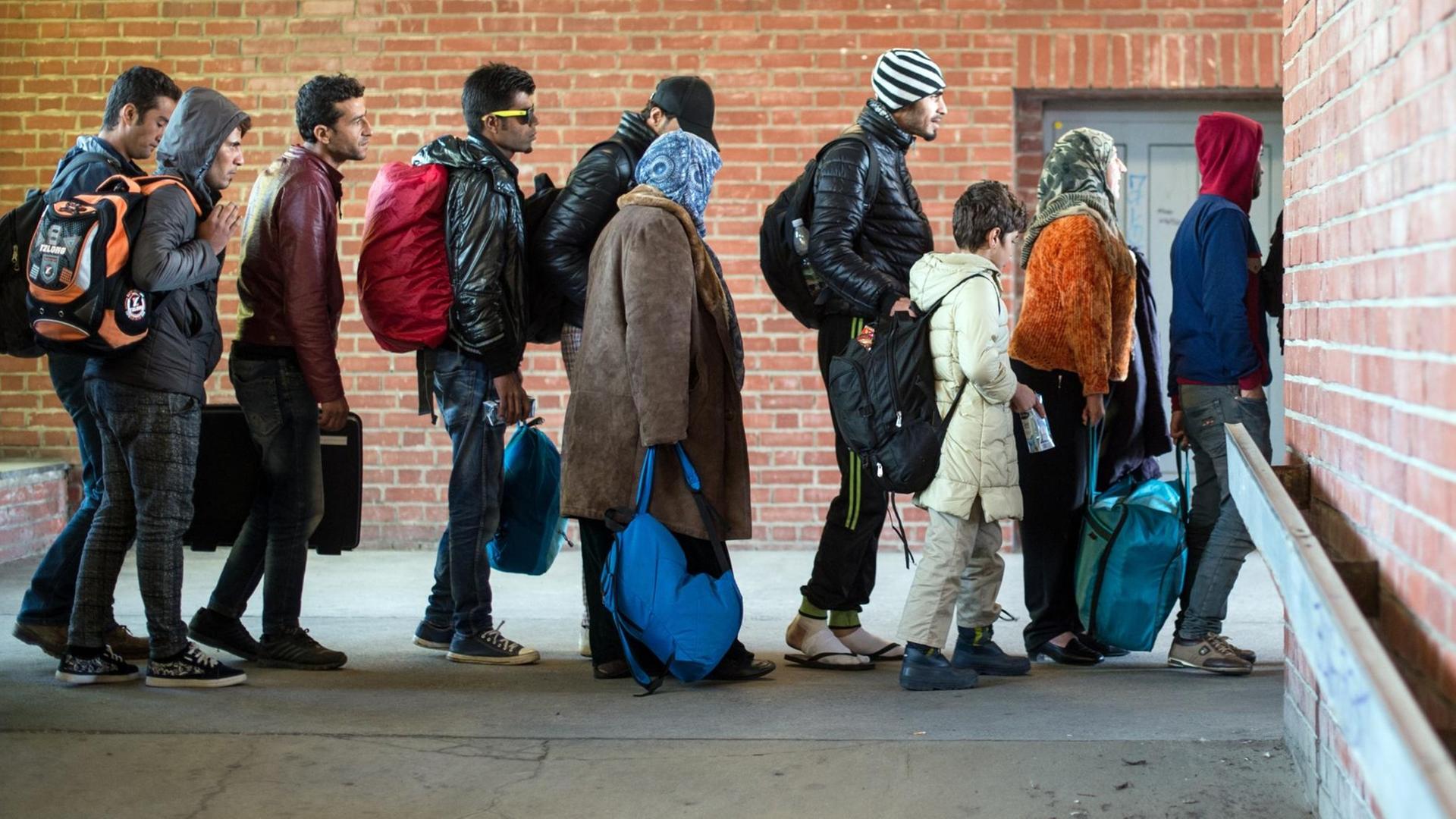 Flüchtlinge warten am Bahnhof in Schönefeld auf ihre Weiterfahrt zur Unterkunft mit Bussen. 
