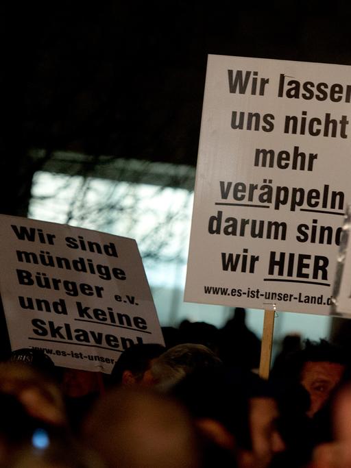 Teilnehmer einer Pegida-Kundgebung mit Plakaten in Dresden