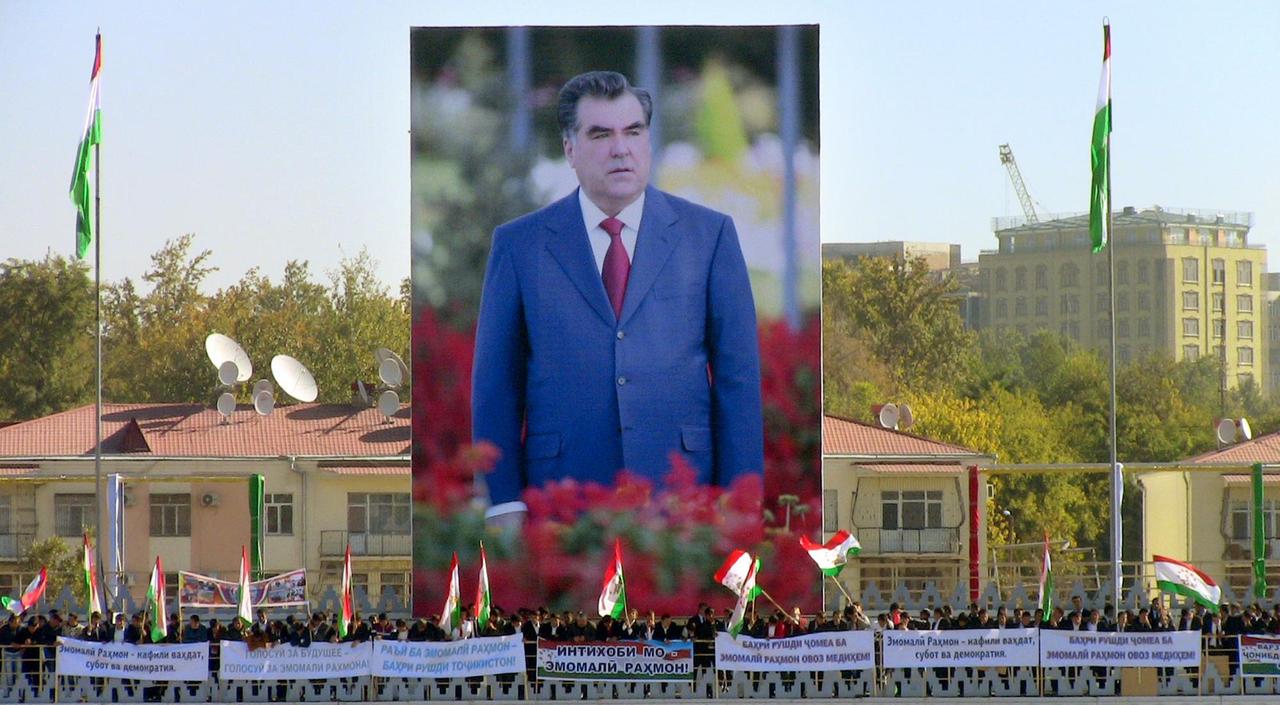 Anhänger von Präsident Emomalii Rahmon schwenken Fahnen vor einem riesigen Plakat des autoritären Präsidenten