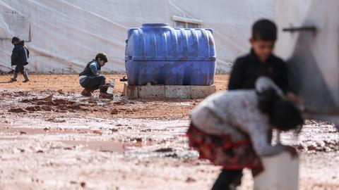 Syrische Kinder füllen in einem provisorischen Lager für Familien, die infolge der Bombardierung und der Militäroperationen aus dem Idlib-Land vertrieben wurden, Krüge mit Wasser auf.