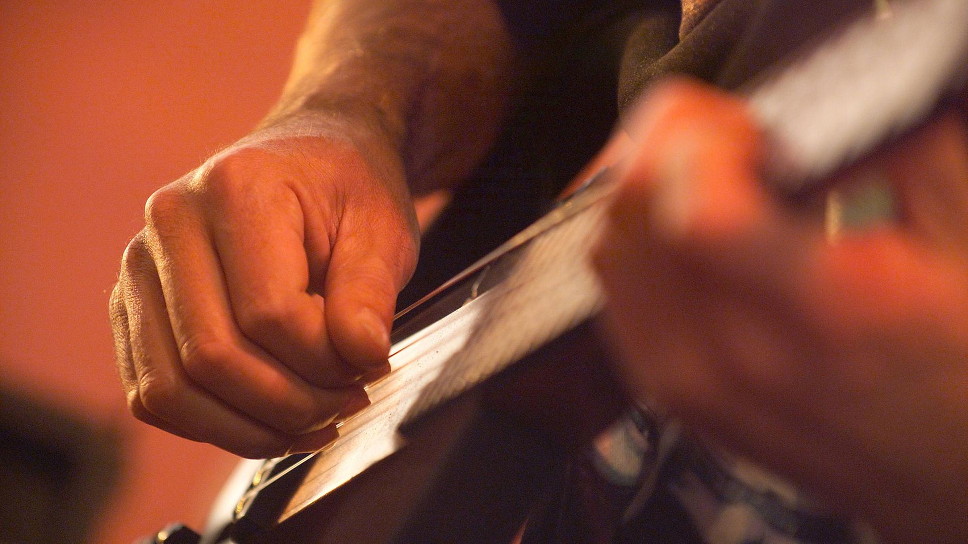 Die Hände eines Musikers beim Gitarre spielen.