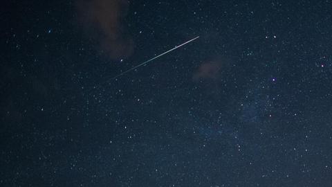 Eine Sternschnuppe leuchtet am Sternenhimmel.