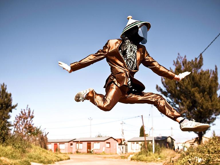 Ein Mann mit Maske springt über eine Straße