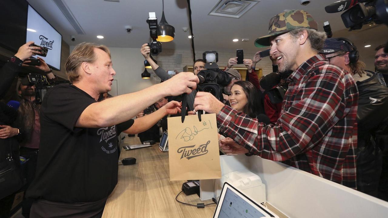 Cannabis-Ladenöffnung in Kanada: Ein Verkäufer reicht einem Kunden eine kleine Papier-Einkaufstüte mit Cannabis über den Tresen