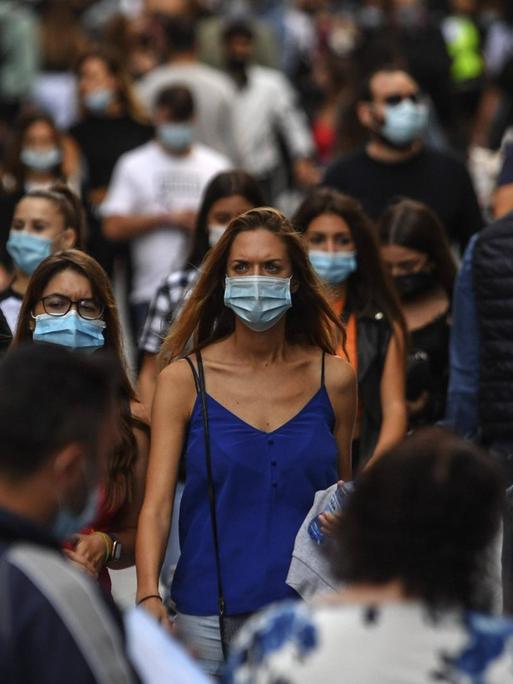 Szene aus Süditalien: Menschen mit Mund-Nasen-Schutz laufen auf einer belebten Straße.