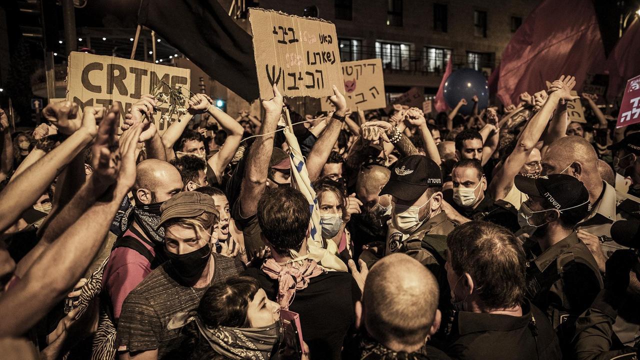 Demonstranten stehen mit Plakaten mit der Aufschrift "Crime" bei Protesten gegen den israelischen Ministerpräsidenten in der Nähe seiner offiziellen Residenz.