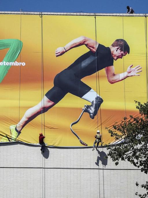 Arbeiter hängen in Brasilia ein Transparent in Vorbereitung auf die Paralympics auf